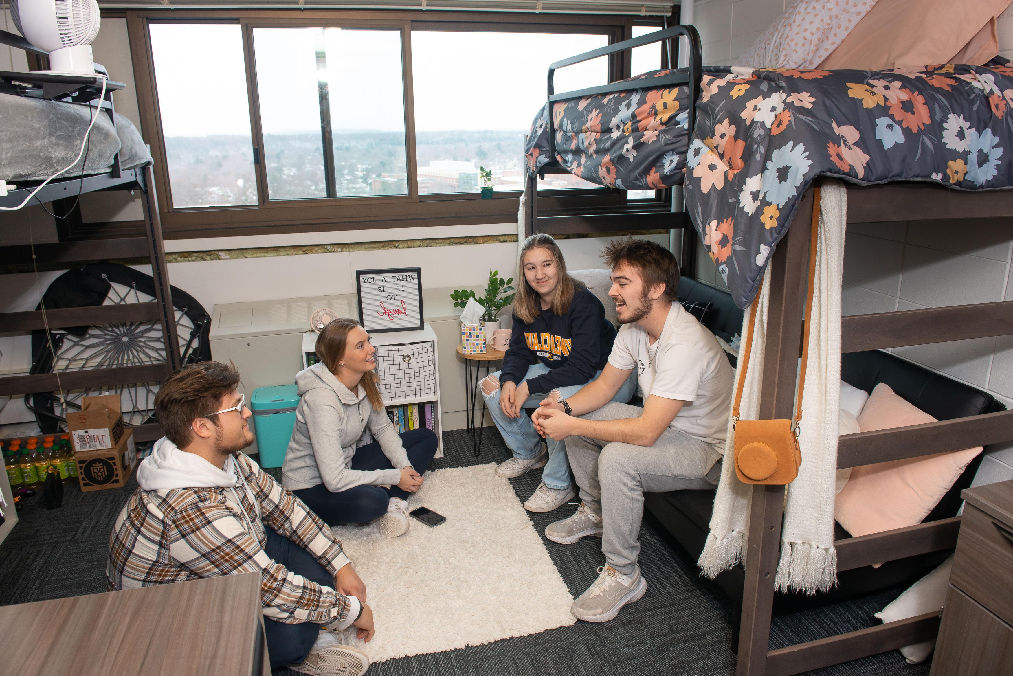 Students sitting toge的r and having a conversation in a residence hall room.