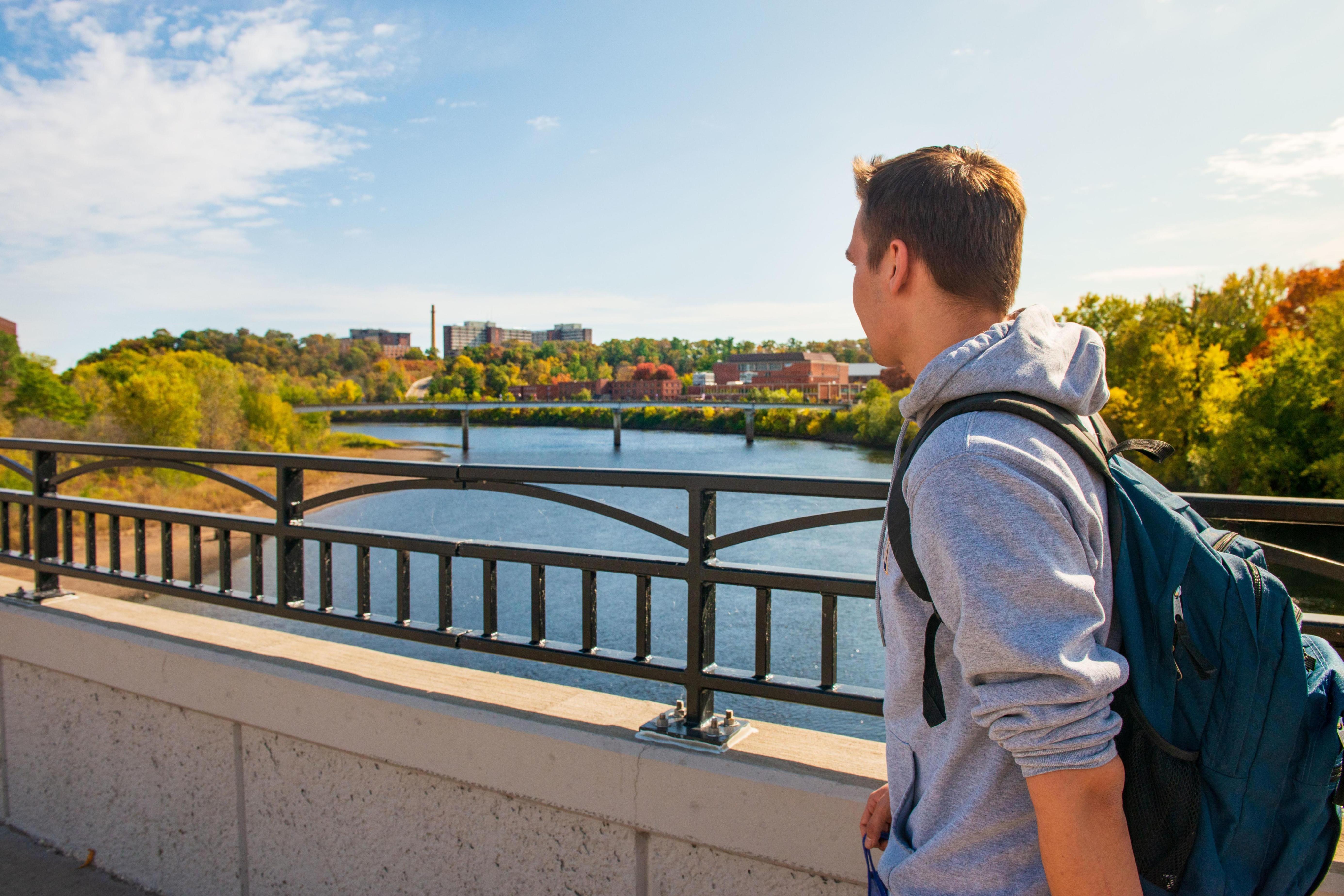 Student crosses foot bridge on a fall day.