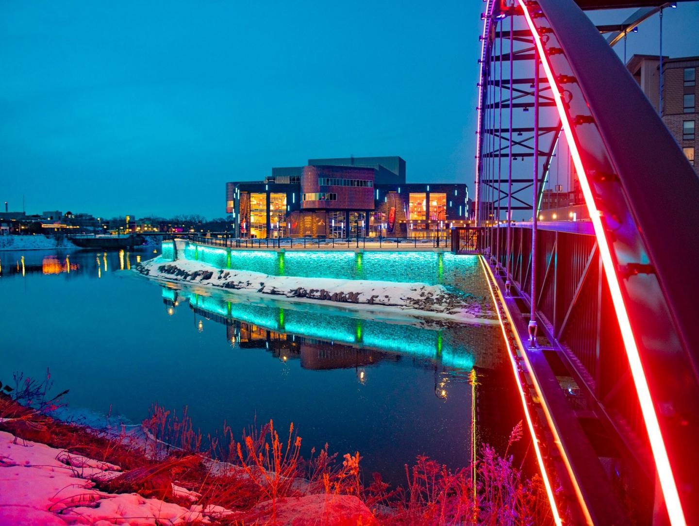 Pablo Center at sunset with colorful lights lighting up the bridge and river